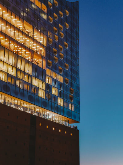 Low angle view of illuminated building against clear blue sky