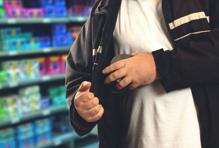 Midsection of man stealing product from store