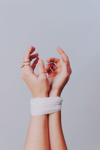 Close-up of tied hands against white background