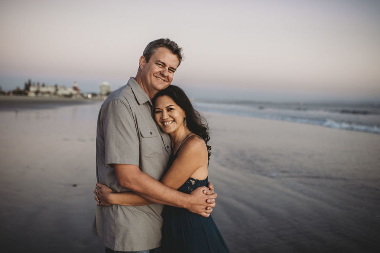 Happy mid-40's couple embracing on ocean beach