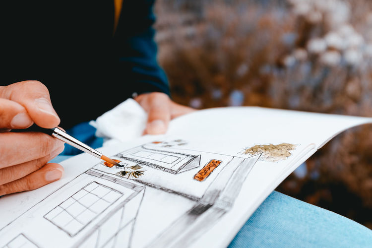 Midsection of woman painting on paper outdoors