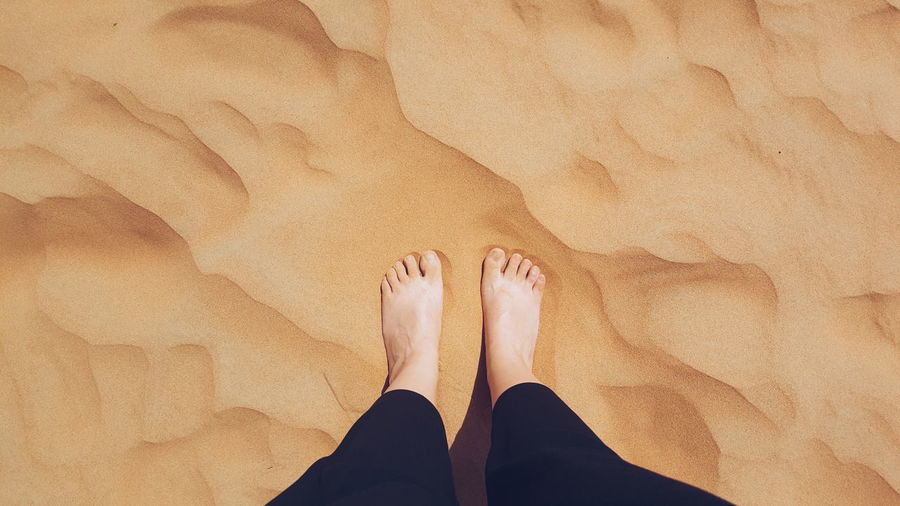Low section of person standing on sand at desert