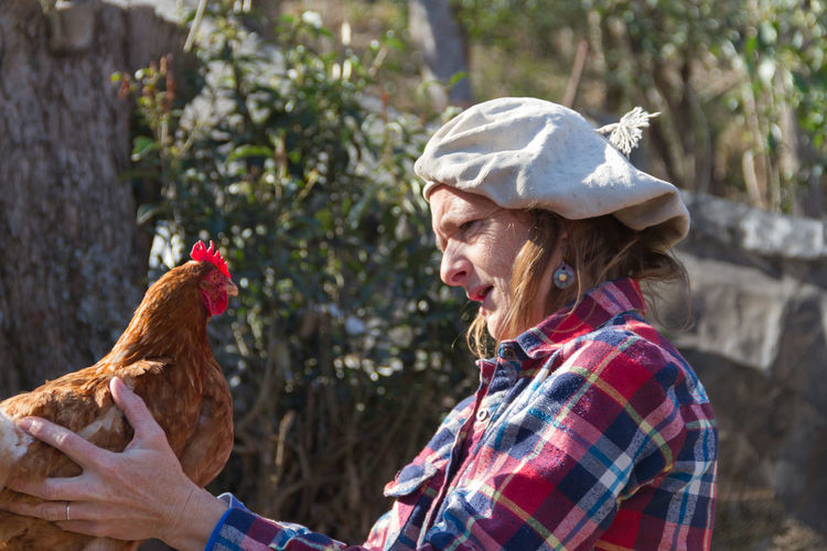 Mature woman with hen at farm