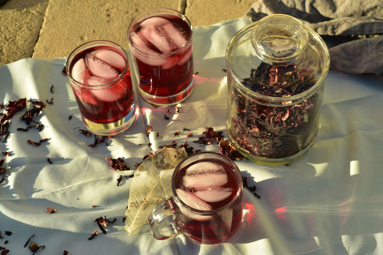 Drinking glasses filled with ice cubes and red color iced tea made with hibiscus flower petals