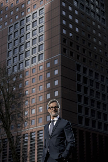 Portrait of businessman standing against building