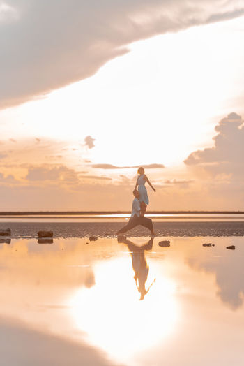 Real people stand in yoga assanas on the seashore at dawn