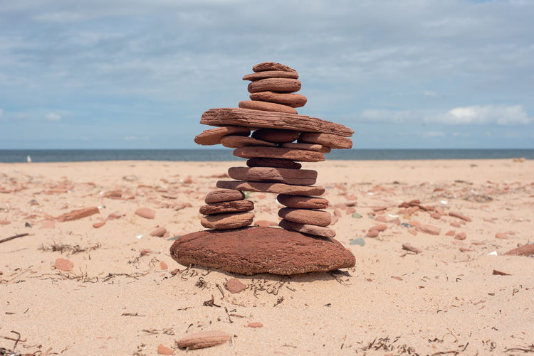 Stack of stones at beach against sky