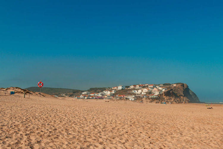 Scenic view of beach against clear blue sky