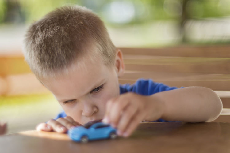 Close-up of cute boy playing with toy car on table