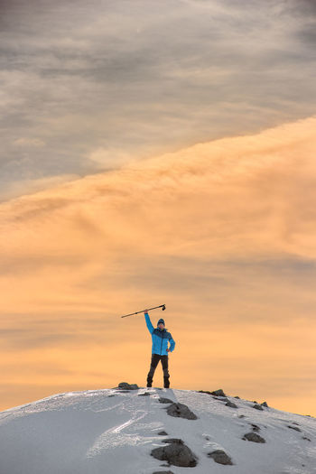 Man standing on snow covered against sky during sunset