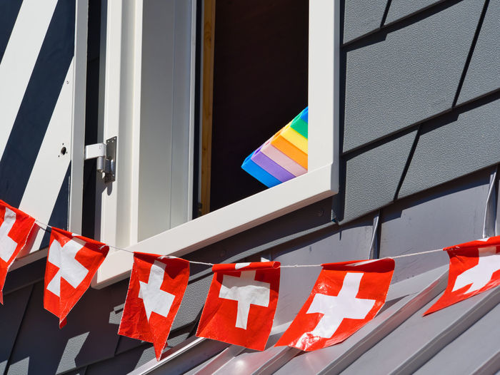 Low angle view of swiss flags by window 