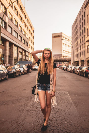 Portrait of young woman standing on road in city