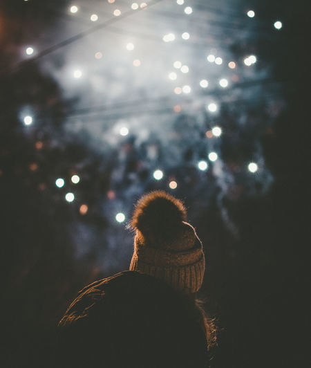 Rear view of woman against illuminated fireworks at night
