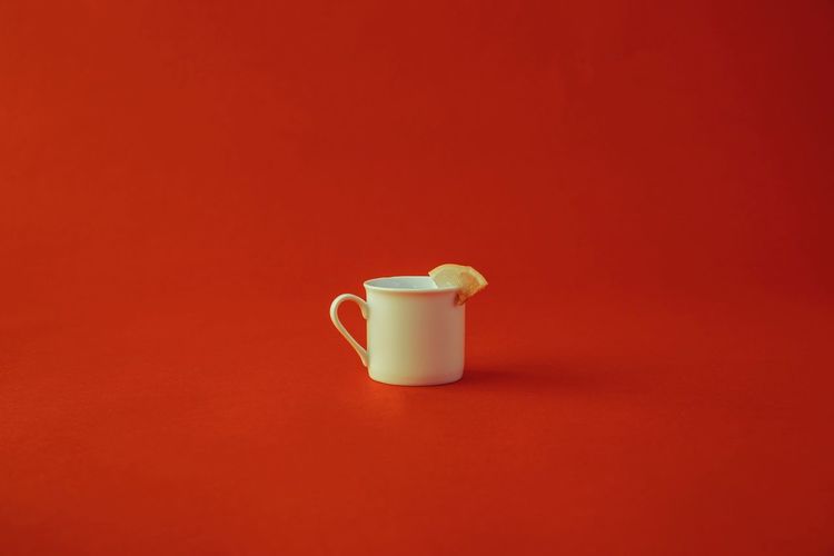 Close-up of coffee cup against red background