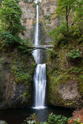 Scenic view of multnomah falls in oregon with one person in red on bridge
