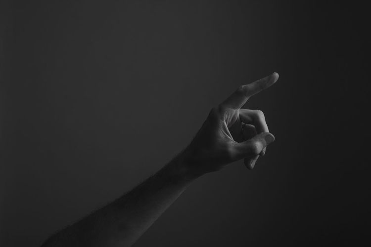 Close-up of human hand gesturing against black background