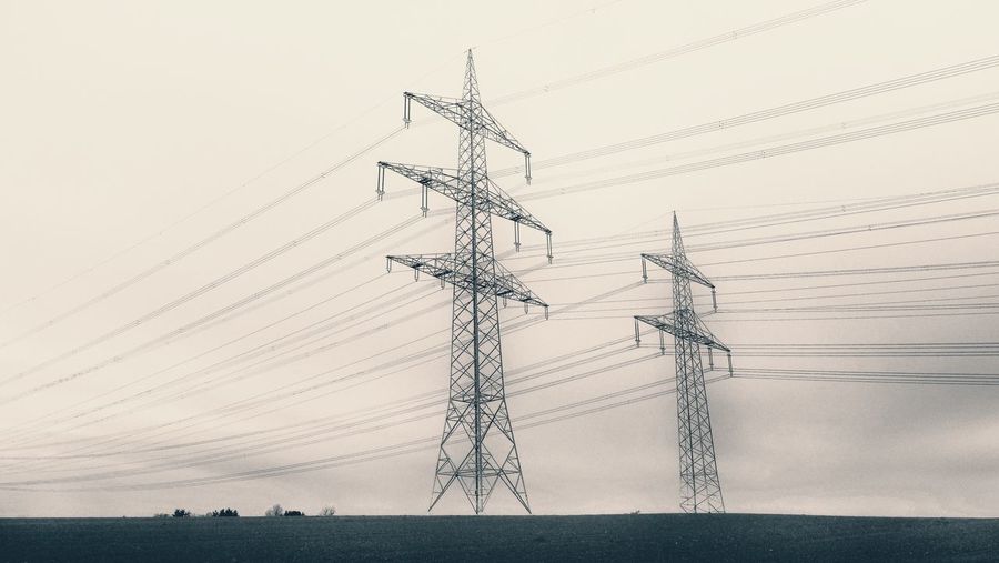 Low angle view of electricity pylon on field against sky