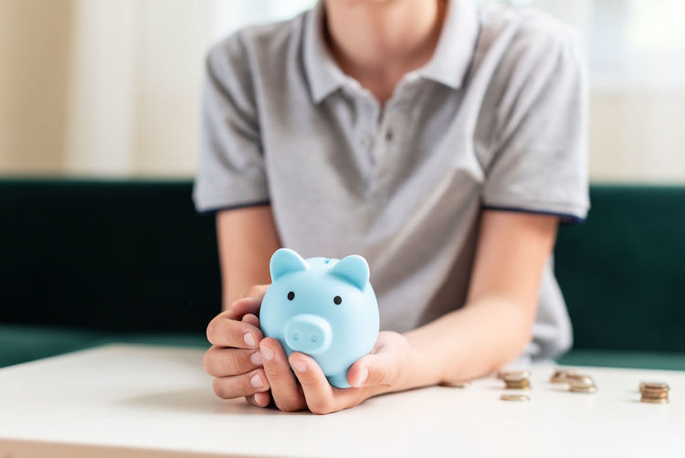 Midsection of man holding piggy bank on table