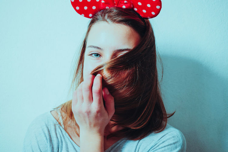 Close-up portrait of young woman with brown hair by wall
