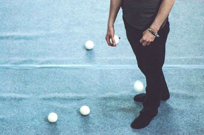 Low section of man holding juggling ball on floor