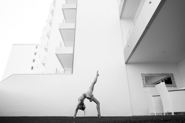 Side view of woman practicing yoga against building