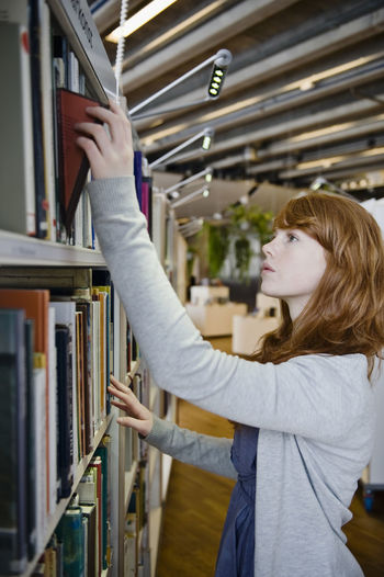 Side view of a young woman reading book