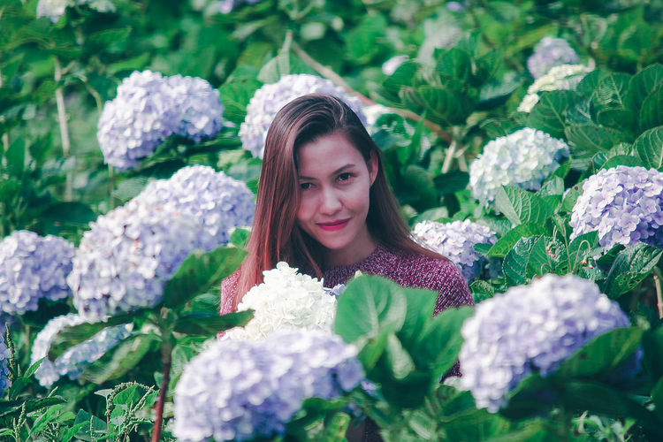 Portrait of smiling woman by flowering plants