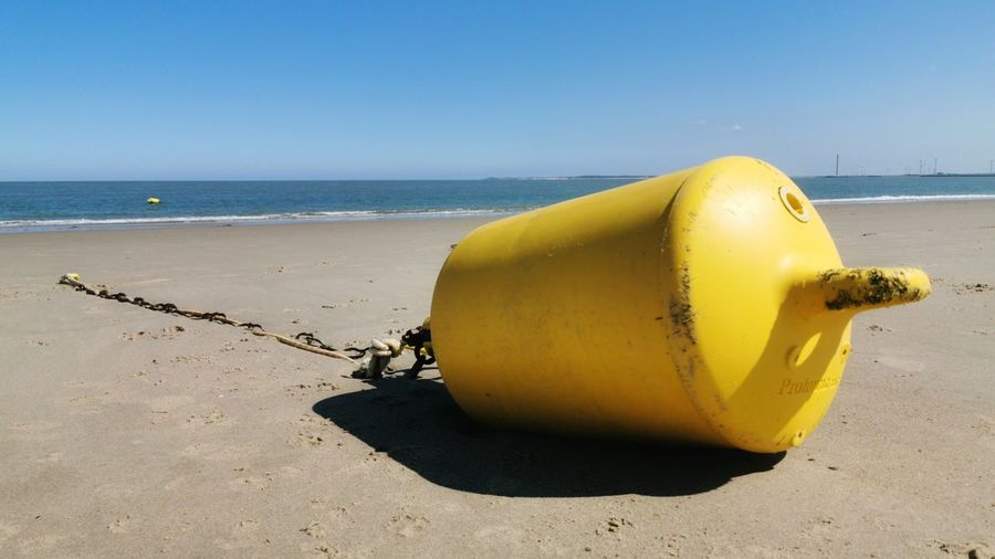 Yellow umbrella on beach against clear sky