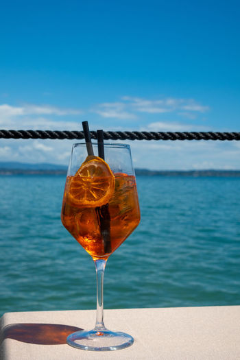 Close-up of drink on table by sea against sky