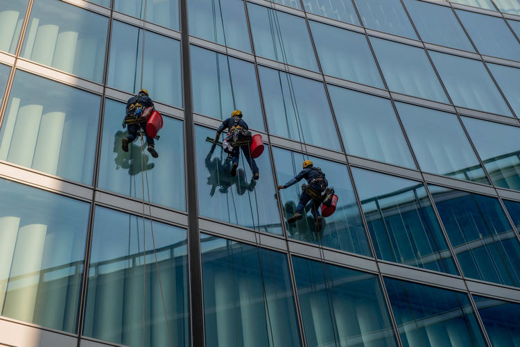 Milan italy march  2021 skilled glass cleaners who lower themselves with slings from above