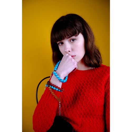 Portrait of beautiful young woman sitting against yellow background