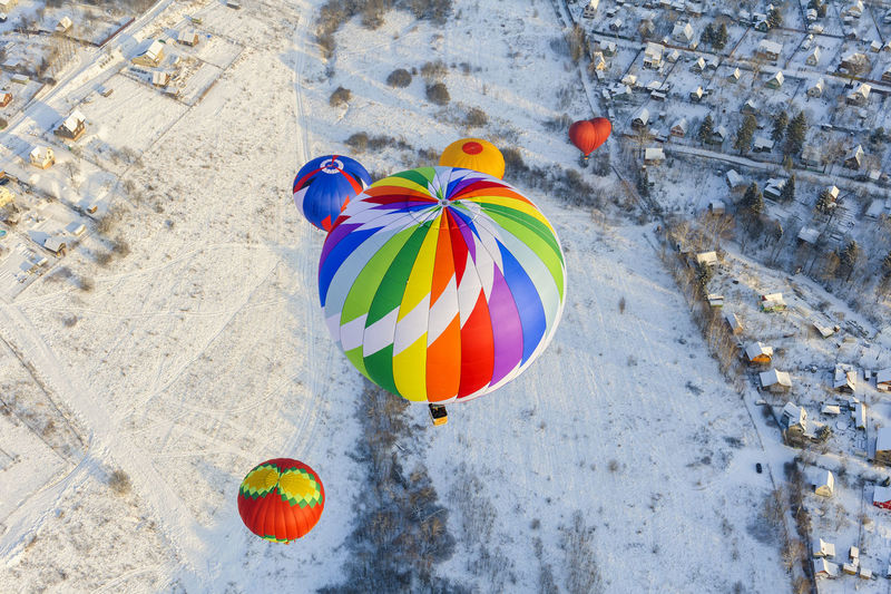 High angle view of hot air balloons flying over snow covered land