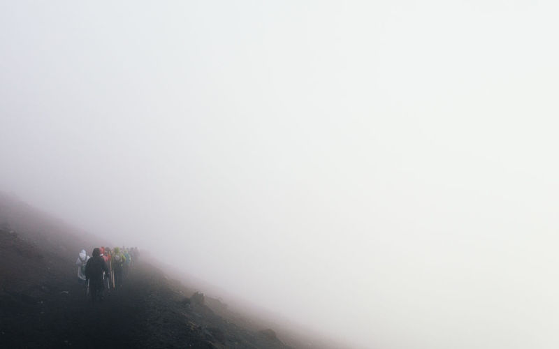 Rear view of people walking on mountain in foggy weather