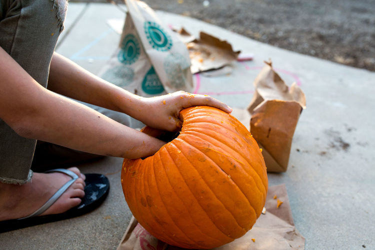 Girl reaches into pumpkin during the carving process