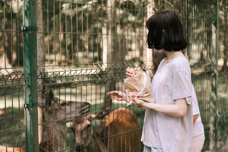 Rear view of woman with arms raised in zoo