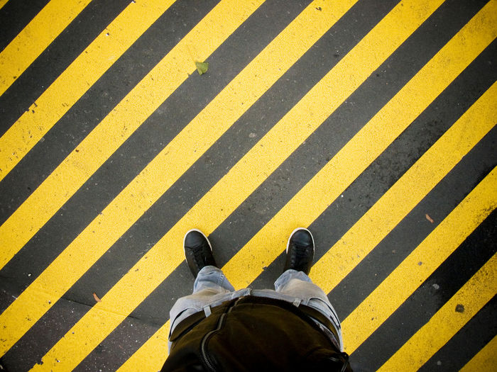 Low section of man standing on crosswalk