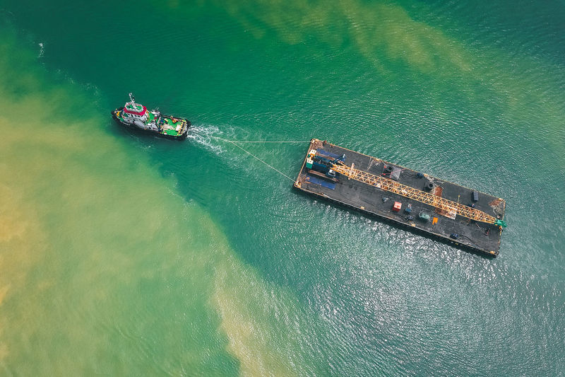 Aerial view of tugboat hauling ship in sea