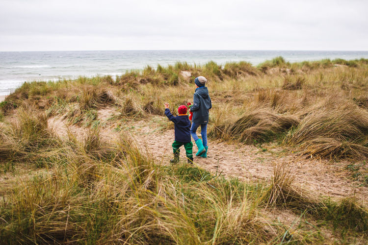 Full length of two boys walking through baltic grassland 