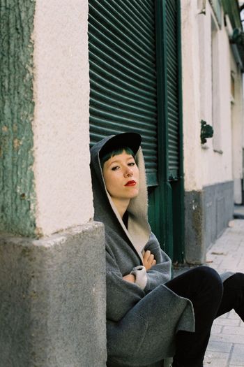 Portrait of punk woman sitting against green shutter