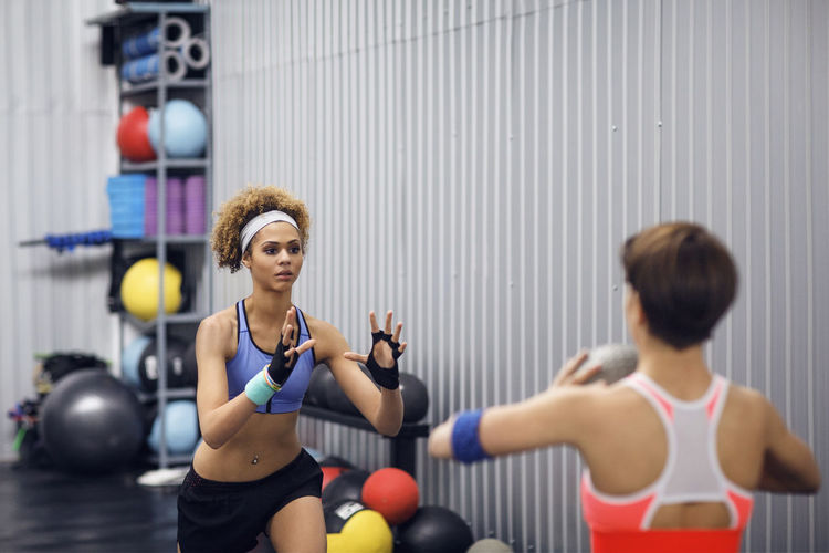 Determined female athletes exercising with medicine ball at gym