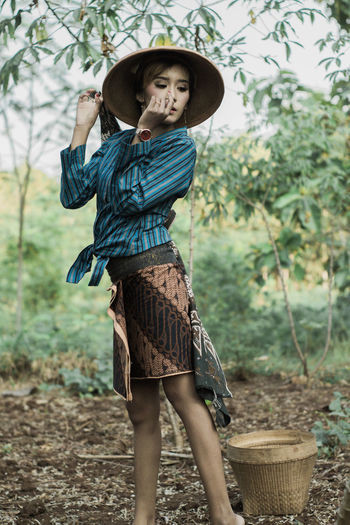 Full length of woman wearing hat standing against plants
