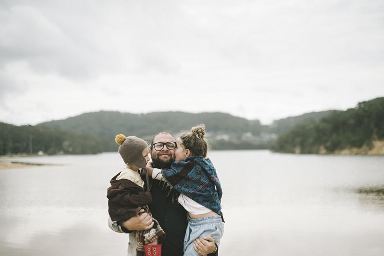 Father with kids standing against lake