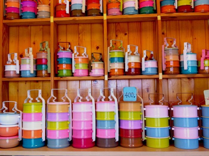 Colorful tiffins on wooden shelves in store