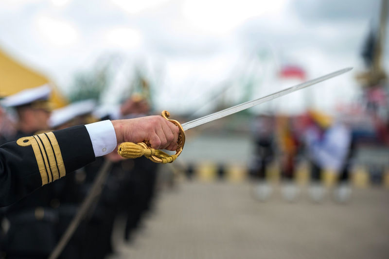 Cropped hand of army soldier holding sword outdoors