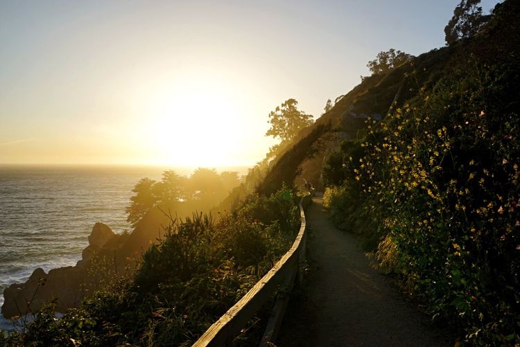 Walkway on mountain by sea during sunset