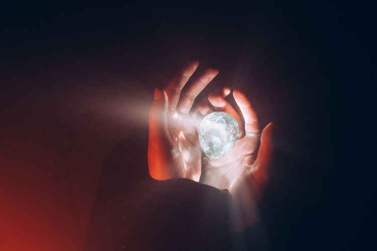 CLOSE-UP OF HUMAN HAND HOLDING ILLUMINATED LIGHT