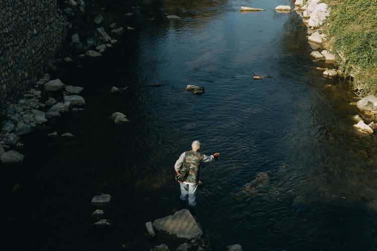 A man fishing next to a river during autumn
