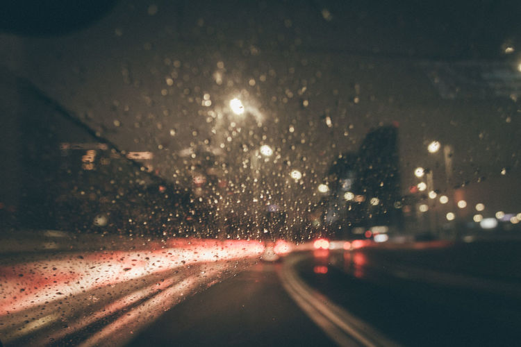 Illuminated road seen through wet window at night