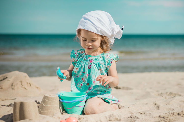 Full length of girl making sandcastles while sitting on beach