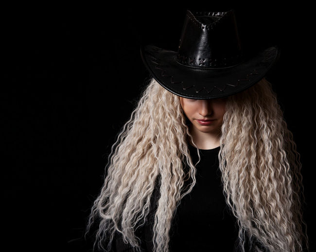 Woman wearing hat against black background